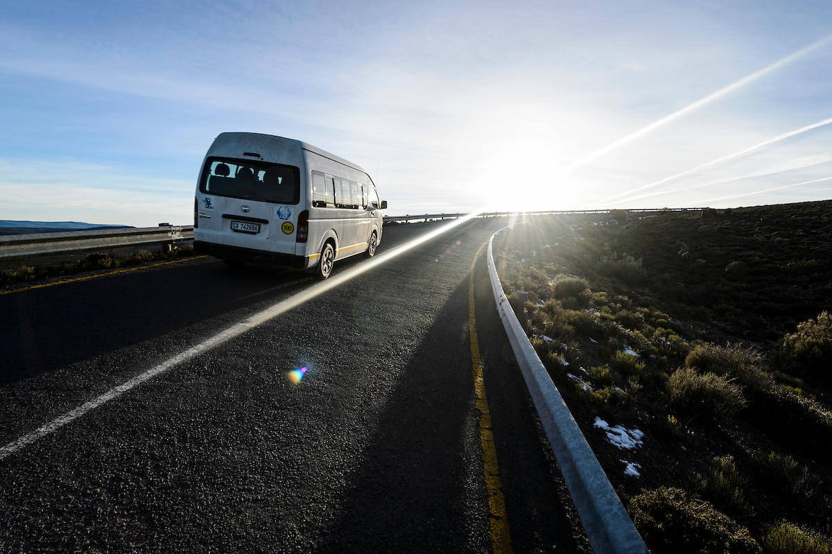 A van transporting local workers travels along the road leading to the Southern African Large Telescope (SALT) during sunrise on July 18, 2017. The photograph is part of a series of stories highlighting the work of University of Wisconsin-Madison researchers in South Africa as they explore the origins of the universe, the first evidence of life on Earth as preserved in the geological record and the evolution of humankind. (Photo by Jeff Miller / UW-Madison)