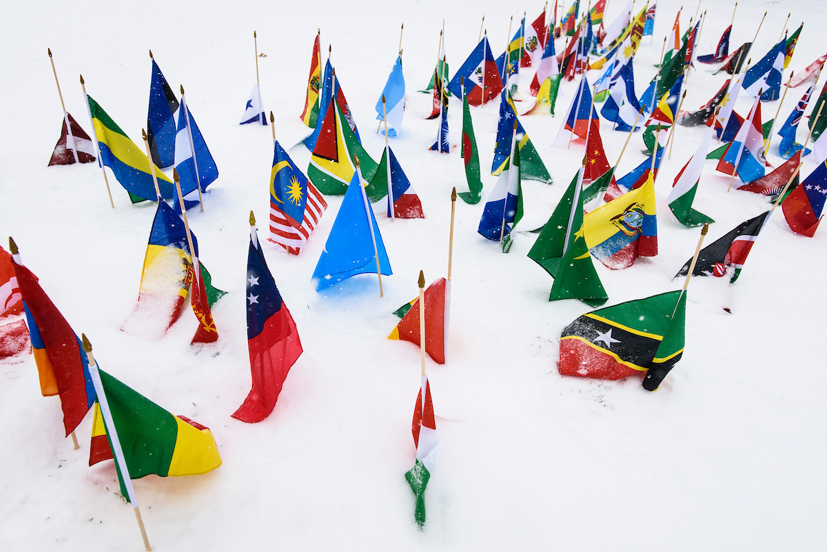 multinational flags planted in the snow on bascom hill.
