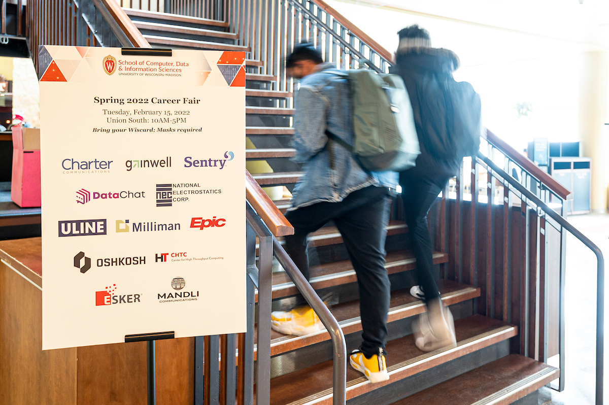 students walking up the stairs in union south with a career fair poster.