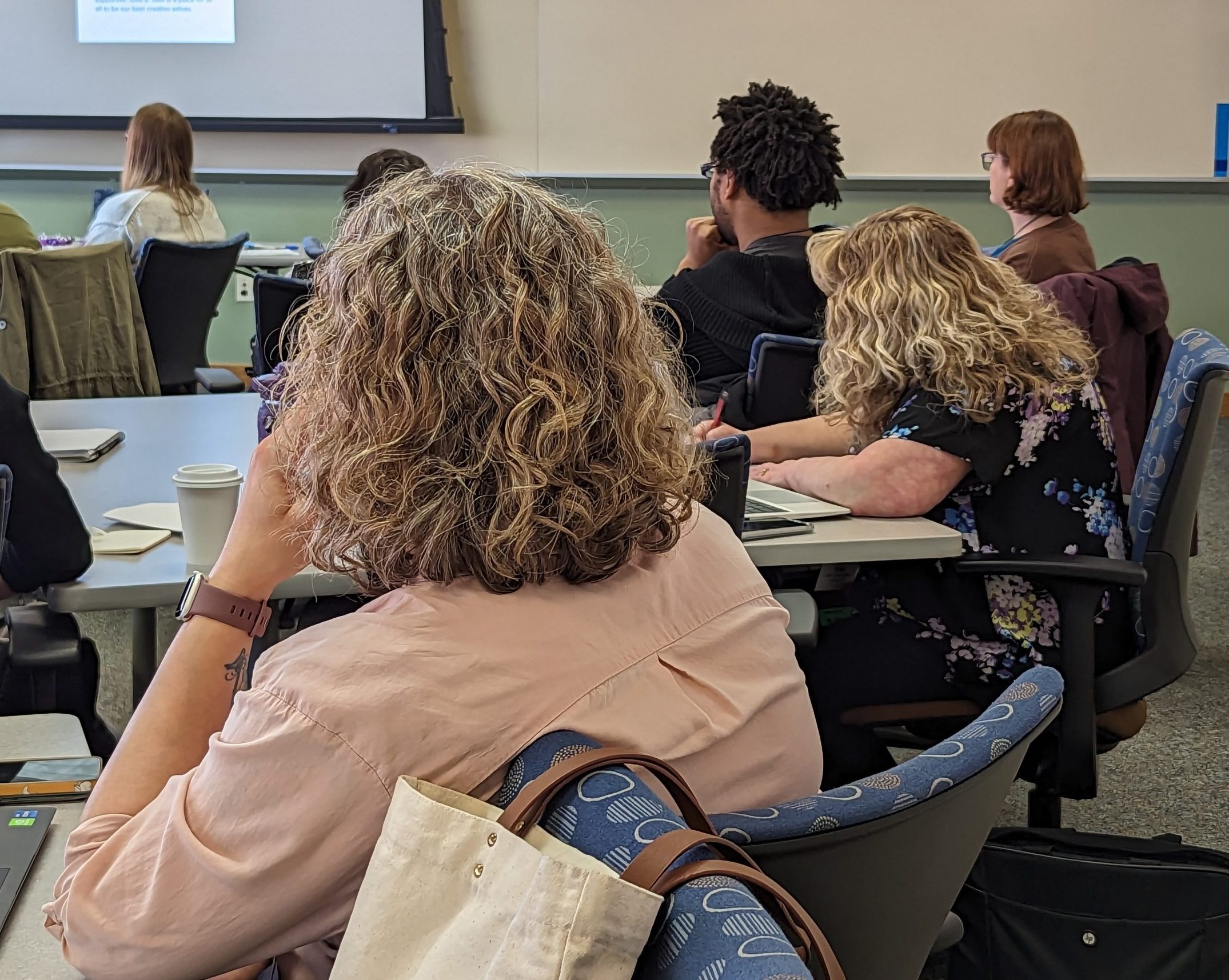 Adult learners are listening to a presentation and taking notes