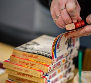 hand with a stamp, stamping books with 'jail library'