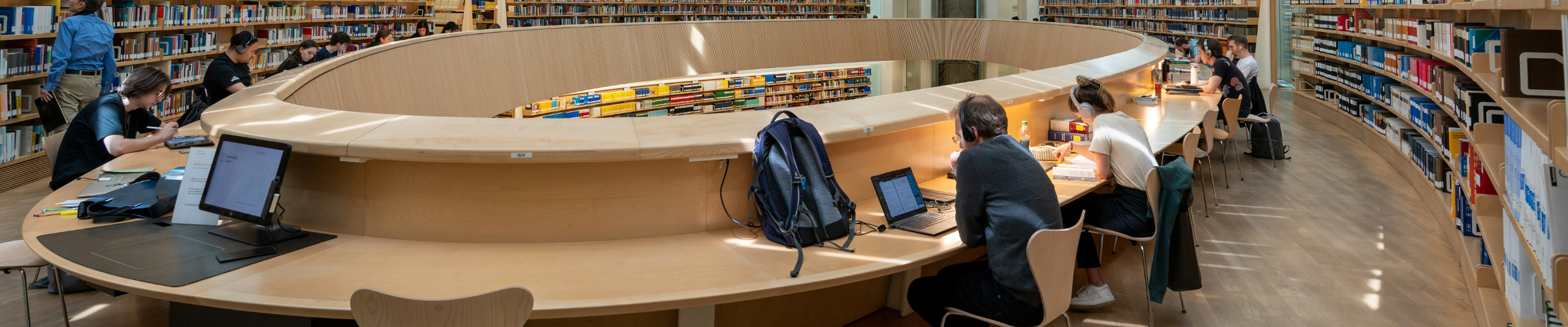 People sitting a laptops and computers in a library working independently