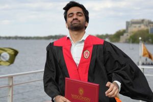 Graduate with robe and degree by lake