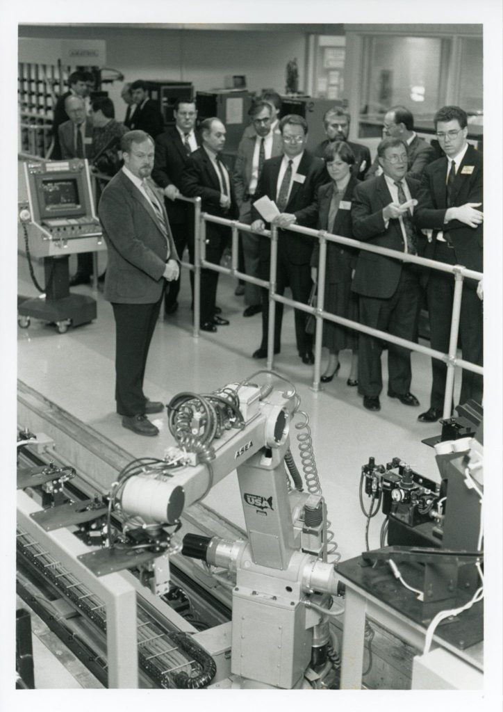 Men standing in a machine shop in black and white photo
